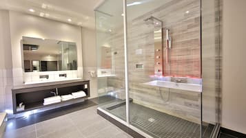 A modern bathroom with a glass-enclosed shower, two sinks, and a large mirror.