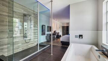 Un baño moderno con ducha de vidrio, una bañera grande y una zona de ducha separada.