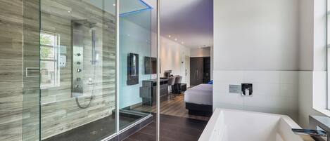 A modern bathroom with a glass-enclosed shower, a large bathtub, and a separate shower area.
