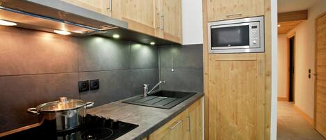 A compact kitchen with wooden cabinets, a built-in microwave, and a stove.