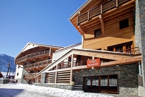 A multi-story wooden building with a reception area, stone walls, and balconies.
