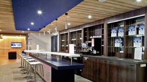 Eine moderne Bar mit einer Theke, Hockstühlen und einer Decke mit Sternenmuster.