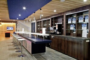 Eine moderne Bar mit einer Theke, Hockstühlen und einer Decke mit Sternenmuster.