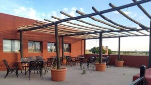An outdoor patio with tables and chairs, a pergola, and potted plants. - Hopi Cultural Center (Second Mesa)