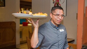A person holding a tray with food items in a restaurant setting. - Hopi Cultural Center (Second Mesa)