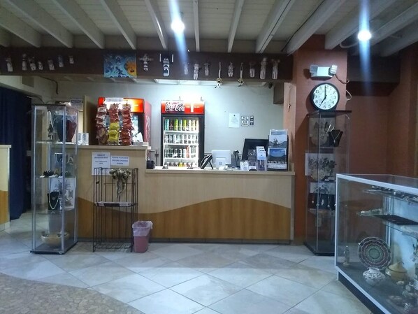A reception area with a Coca-Cola refrigerator, a clock, and a display case with items. - Hopi Cultural Center (Second Mesa)