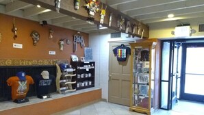 A reception area with a tiled floor, a counter displaying hats and a t-shirt, and a door leading to another room. - Hopi Cultural Center (Second Mesa)
