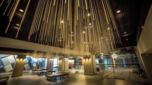 A spacious lobby with hanging light fixtures, seating areas, and a staircase leading to upper levels. - Renaissance Reno Downtown Hotel & Spa (Reno)