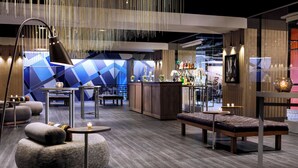 A modern lounge area with seating, a bar, and a geometric wall design. - Renaissance Reno Downtown Hotel & Spa (Reno)