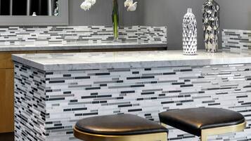 A modern kitchen with a tiled backsplash, two stools, and decorative vases.