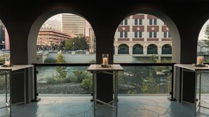 A terrace with a view of a river and buildings, featuring a table with a candle and a glass. - Renaissance Reno Downtown Hotel & Spa (Reno)
