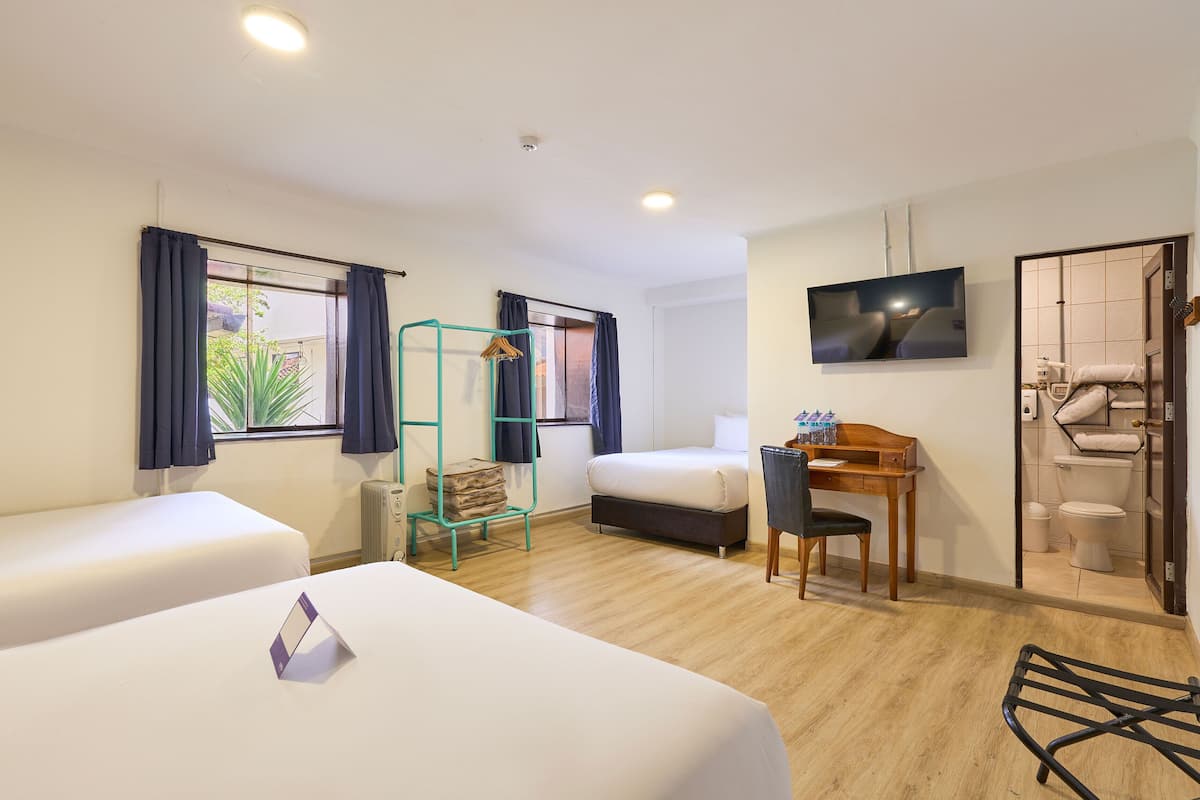 Une chambre d’hôtel avec deux lits, un bureau, une chaise, une télévision et une salle de bain.