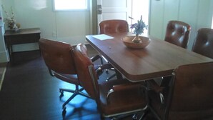 A conference room with a wooden table, six leather chairs, a white door, and a window. - Canora Home Rentals Holiday Cottage (Canora)