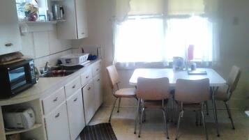 A compact kitchen with white cabinets, a microwave, and a dining table with four chairs.