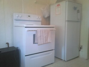A kitchen with a white stove, oven, and refrigerator.