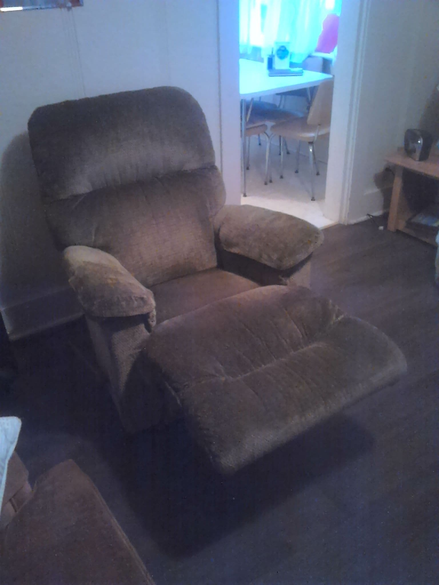 A brown recliner chair with a footrest in a room with a wooden floor.