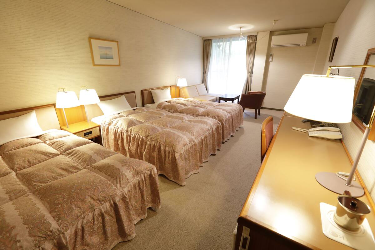 Une chambre d’hôtel avec deux lits, un bureau avec une lampe, une chaise et un téléviseur.