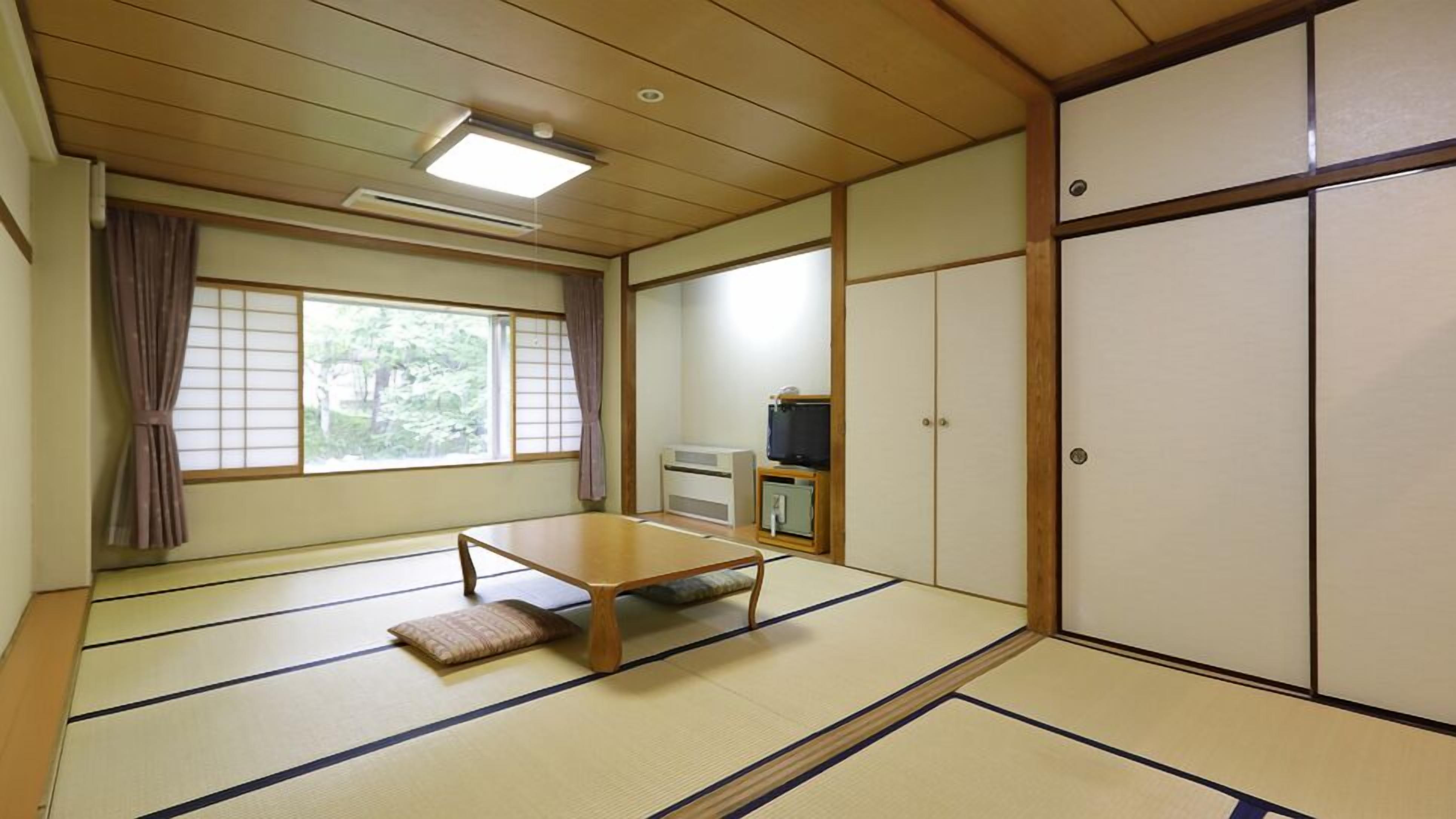 Perinteinen japanilainen huone, jossa on tatamimatto, matala pöytä, liukuvat ovet ja televisio.