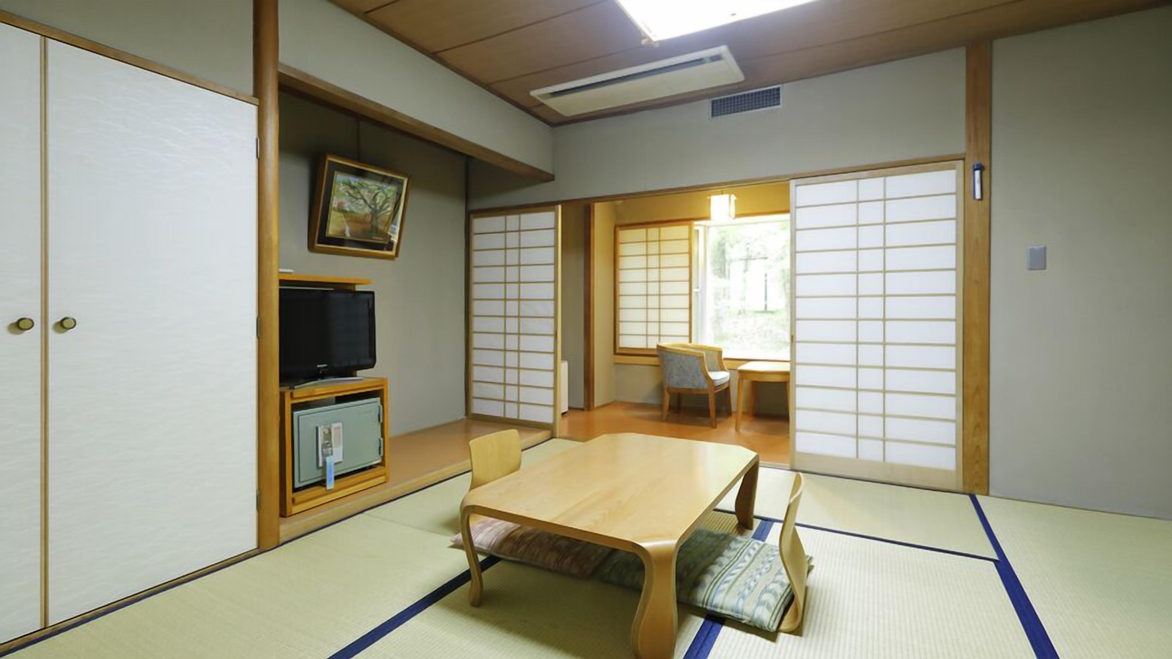 Perinteinen japanilainen huone, jossa on tatamimatto, matala pöytä, televisiotauluko, ja liukuovet.