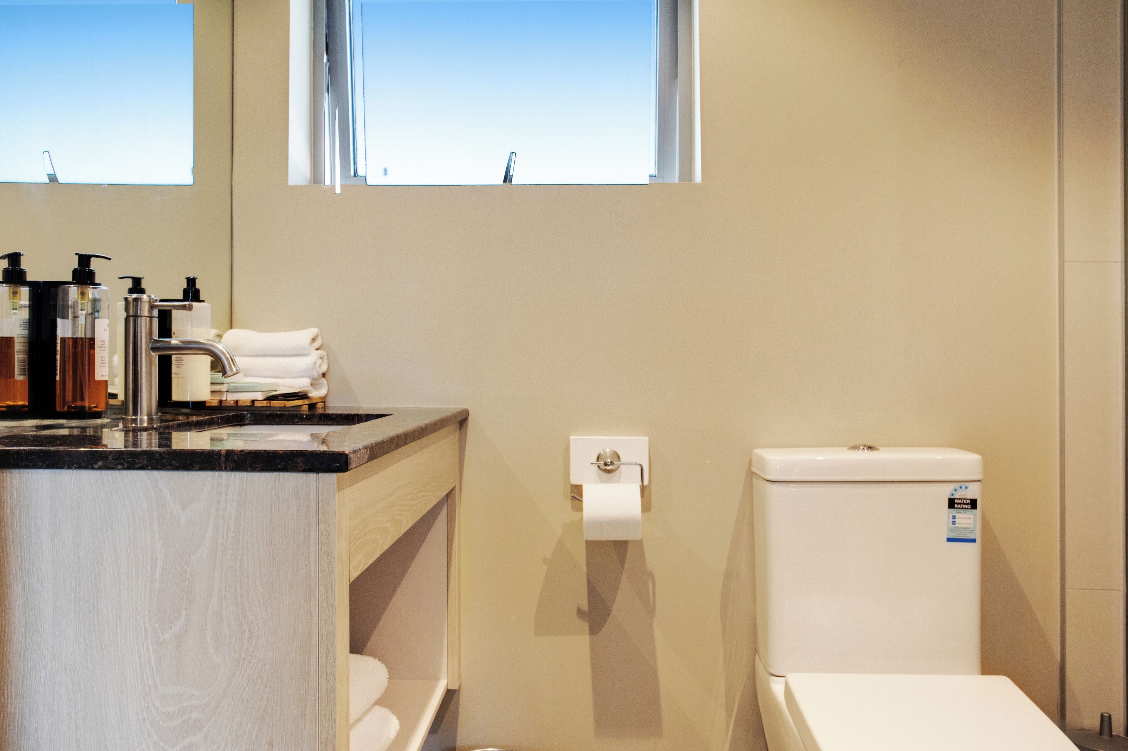 A bathroom with a toilet, sink, and window.