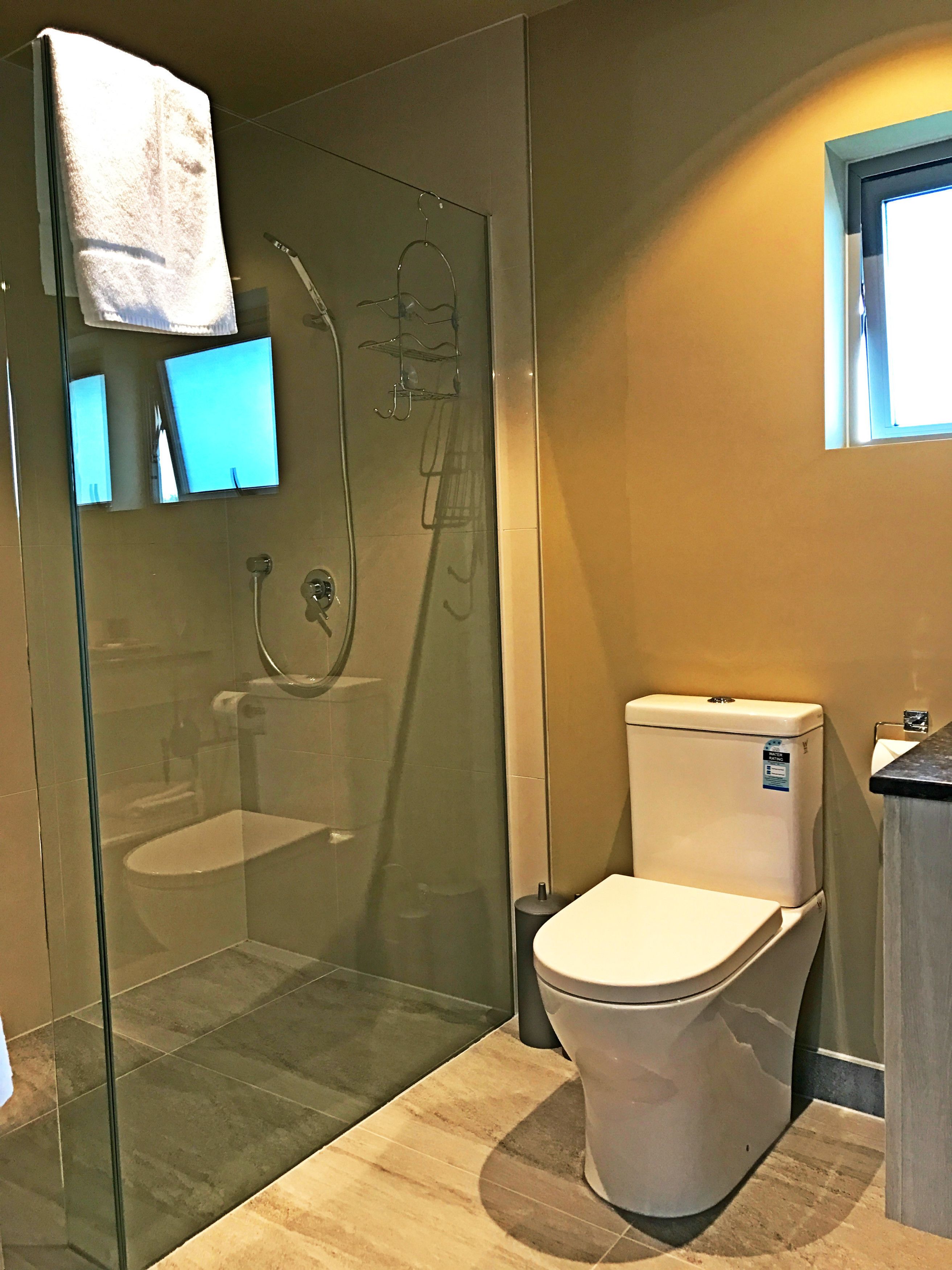Un bany modern amb un espai de banyera de vidre, un vàter i un lavabo.