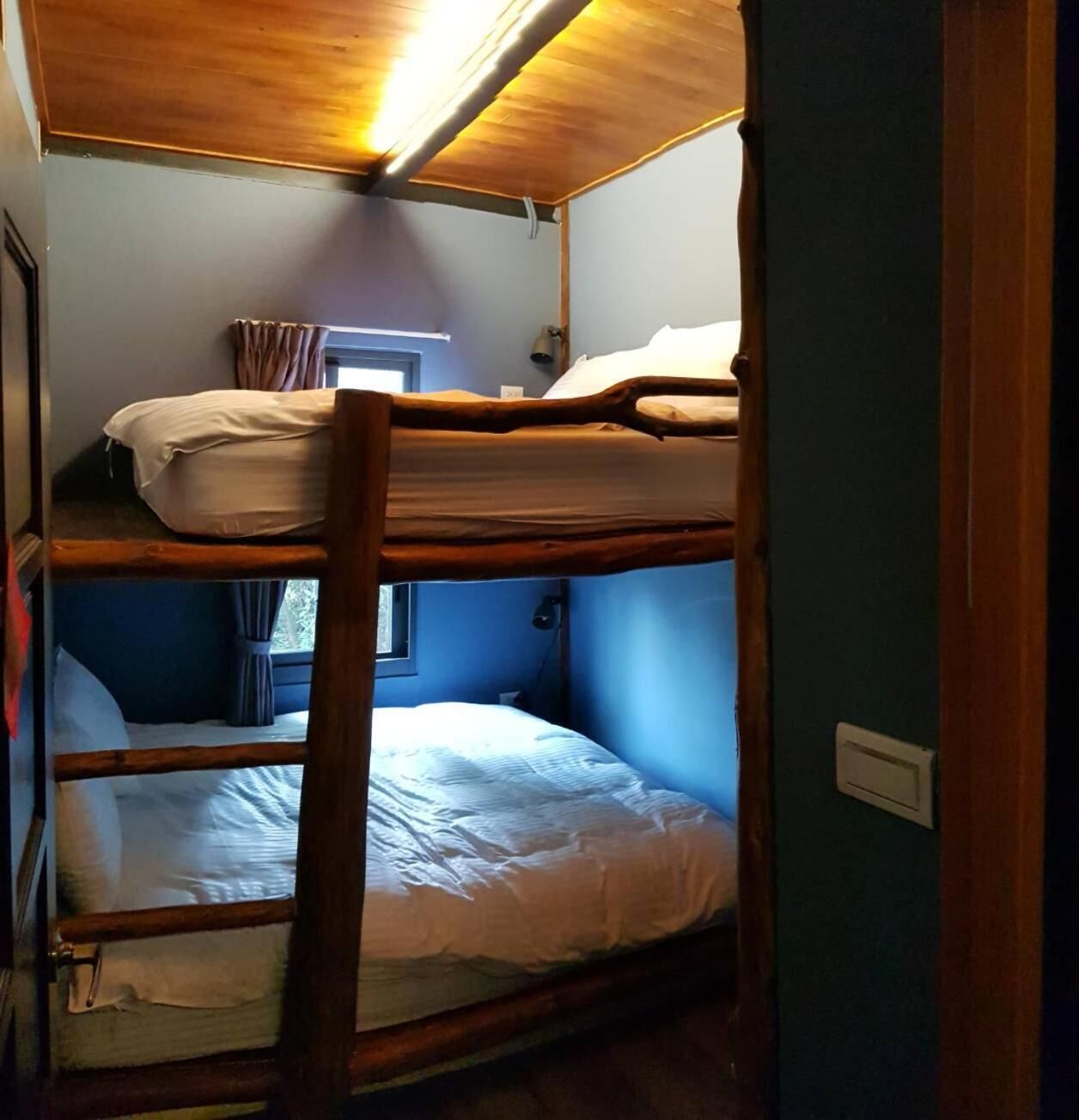 Une chambre avec un lit superposé, dotée de rampes en bois et d’une fenêtre.