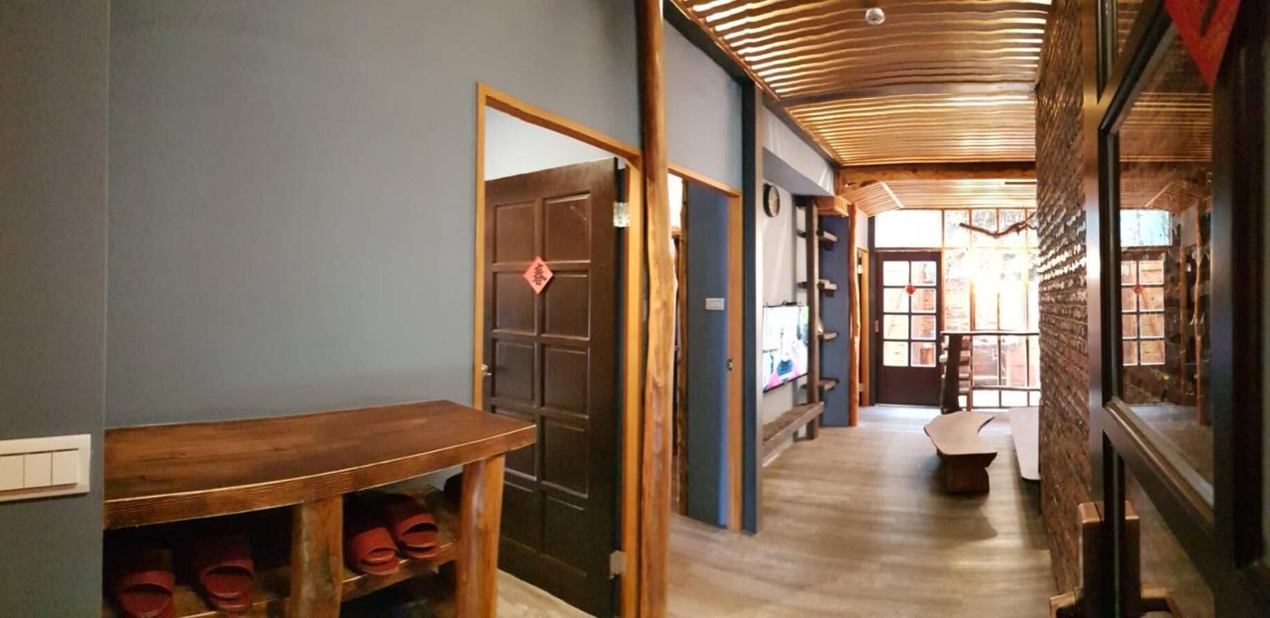 A hallway with a wooden bench, a shoe rack, and a door with a red symbol.