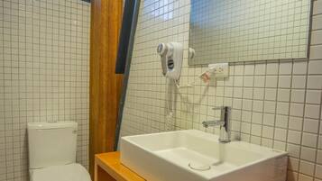 A bathroom with a white toilet, a wooden vanity with a sink, and a mirror above the sink.