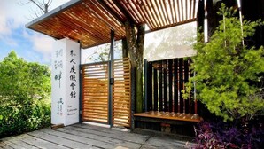 Een houten terras met een pergola, een houten poort en een bord met Chinese karakters.