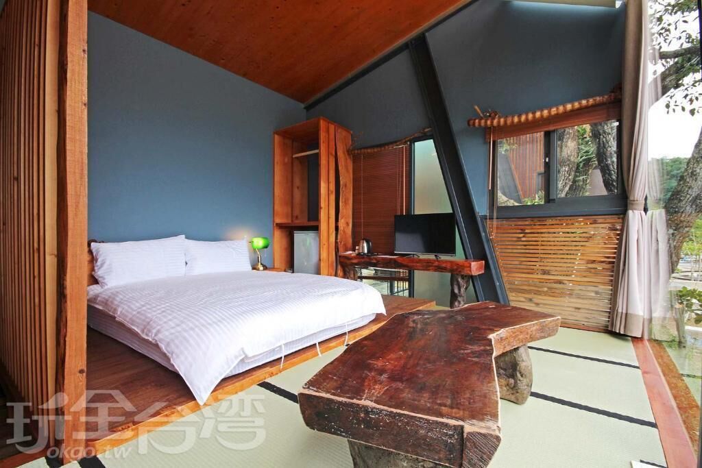 A bedroom with a bed, wooden furniture, and a view of the outdoors.