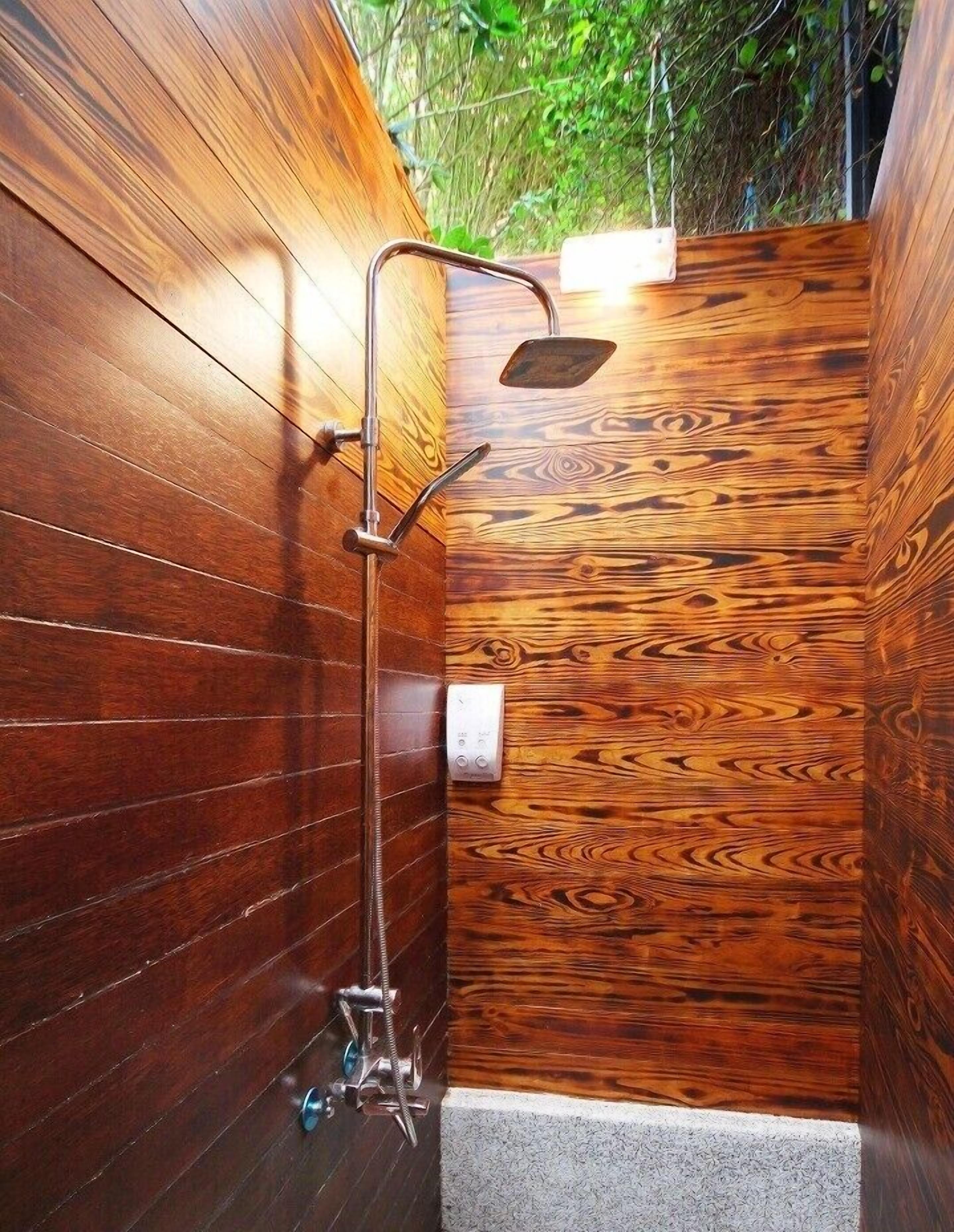 Aseo de madera con ducha de lluvia e hidromasaje de mano.