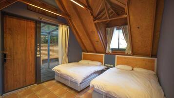 Ein Schlafzimmer mit zwei Betten, einer Holzbalkendecke und einer Schiebeglastür, die zu einem Außenbereich führt.