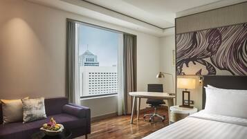Ein Hotelzimmer mit Bett, Sofa, Esstisch, Stuhl und einem kleinen Tisch mit Obst.