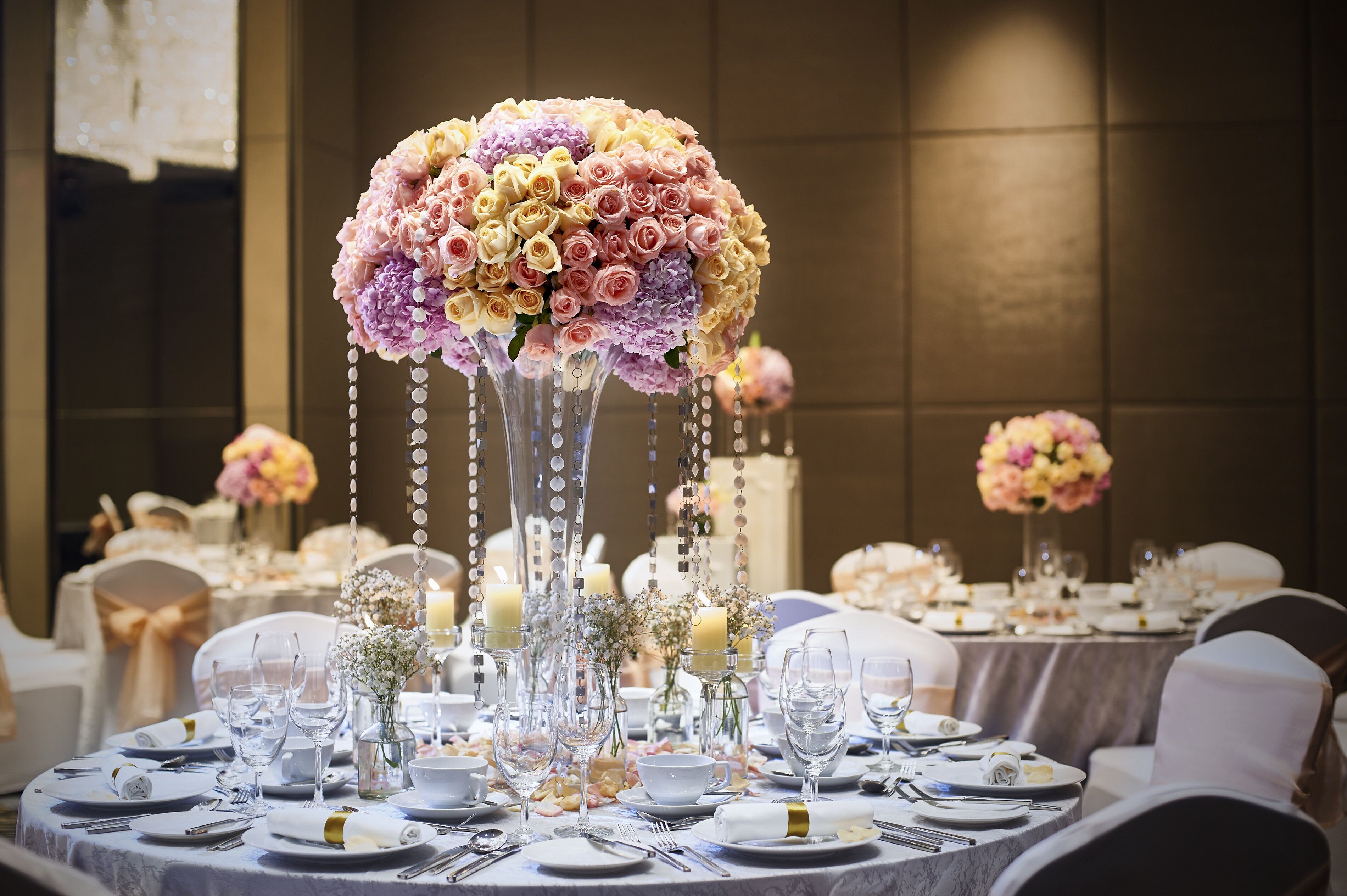 A banquet table set with fine china, glassware, and elegant floral centerpieces.