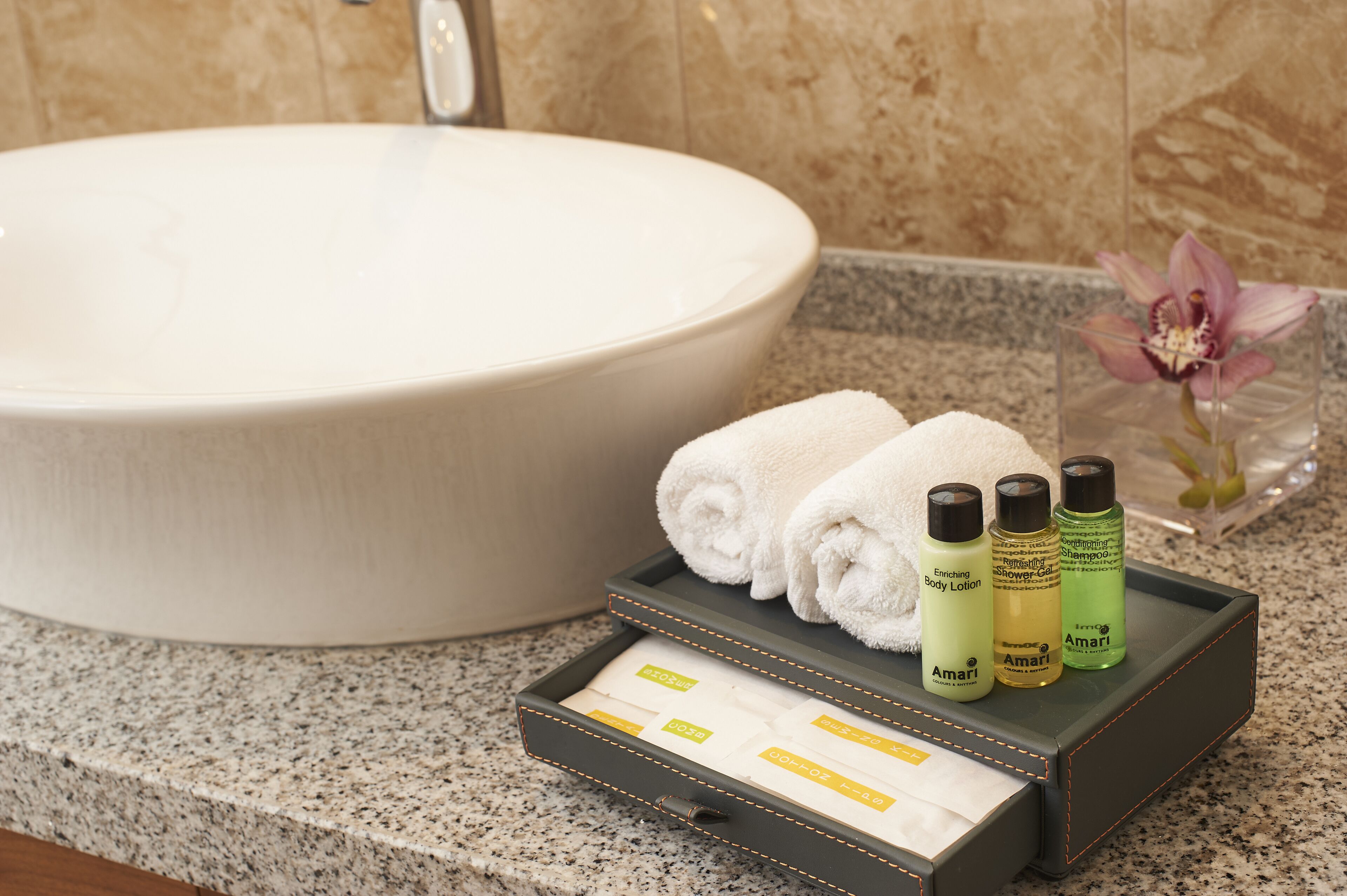 A bathroom with a large sink, a tray with toiletries, and a flower vase.