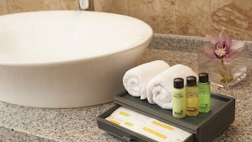 A bathroom with a large sink, a tray with toiletries, and a flower vase.