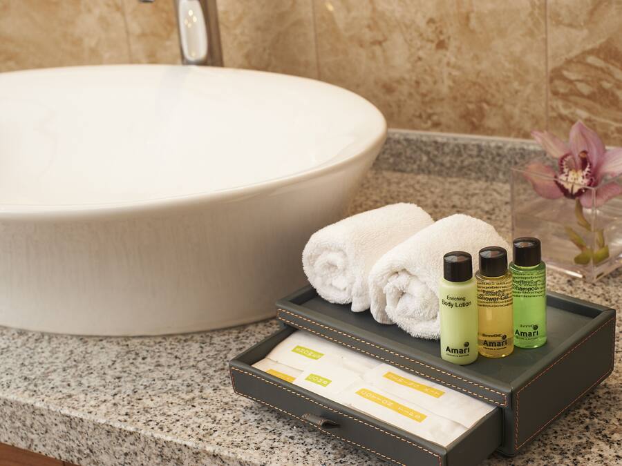 A bathroom with a large sink, a tray with toiletries, and a flower vase.