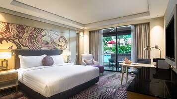 Quarto de hotel com uma cama grande, uma escrivaninha, uma cadeira e uma televisão.