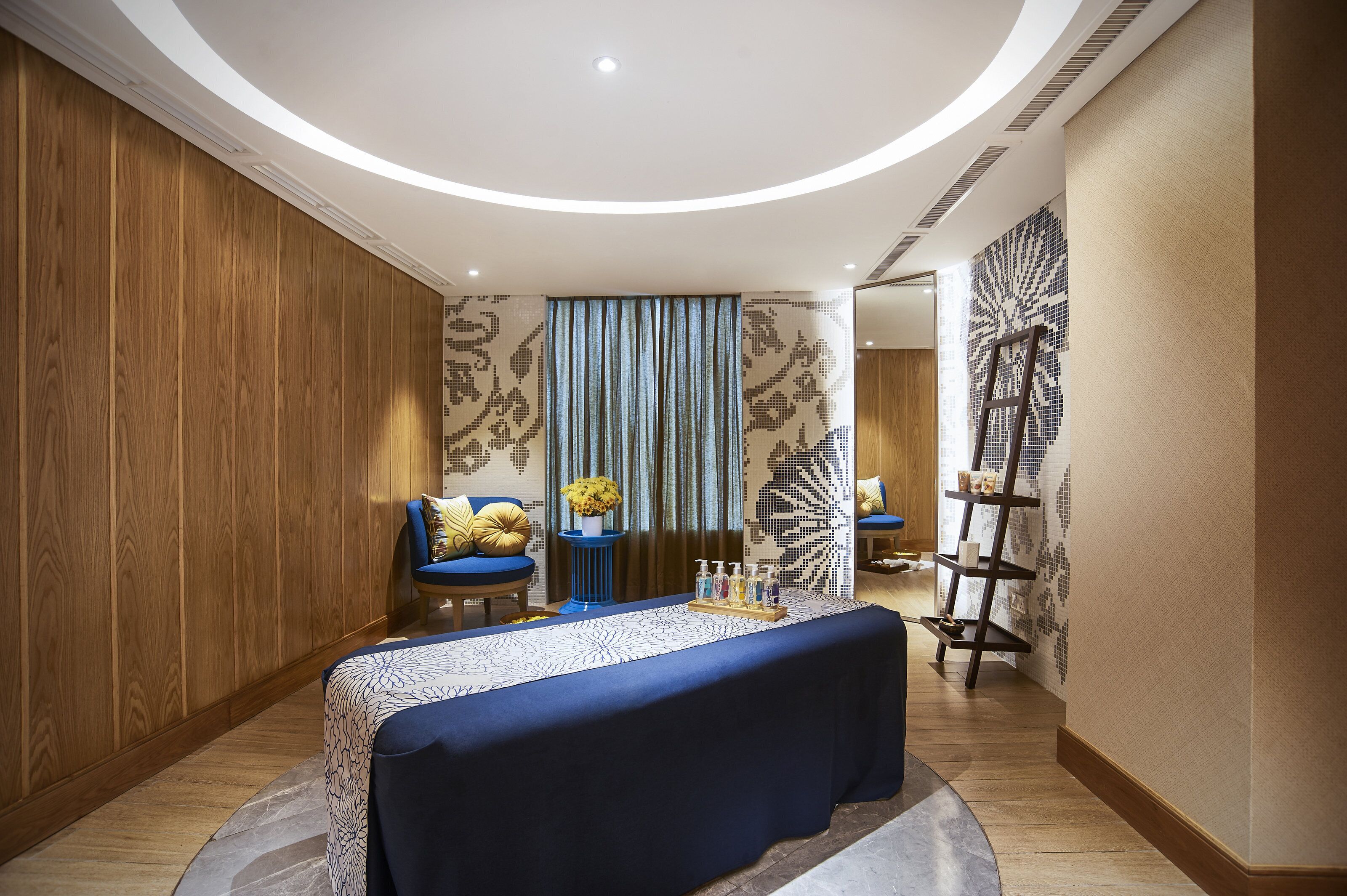 Una habitación moderna con un panel de madera en la pared, un sofá azul, una mesa redonda con mantel azul y un elemento decorativo en la pared.