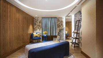 Una habitación moderna con un panel de madera en la pared, un sofá azul, una mesa redonda con mantel azul y un elemento decorativo en la pared.