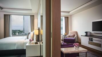 A hotel room with a bed, a desk, a chair, a television, and a view of a cityscape.