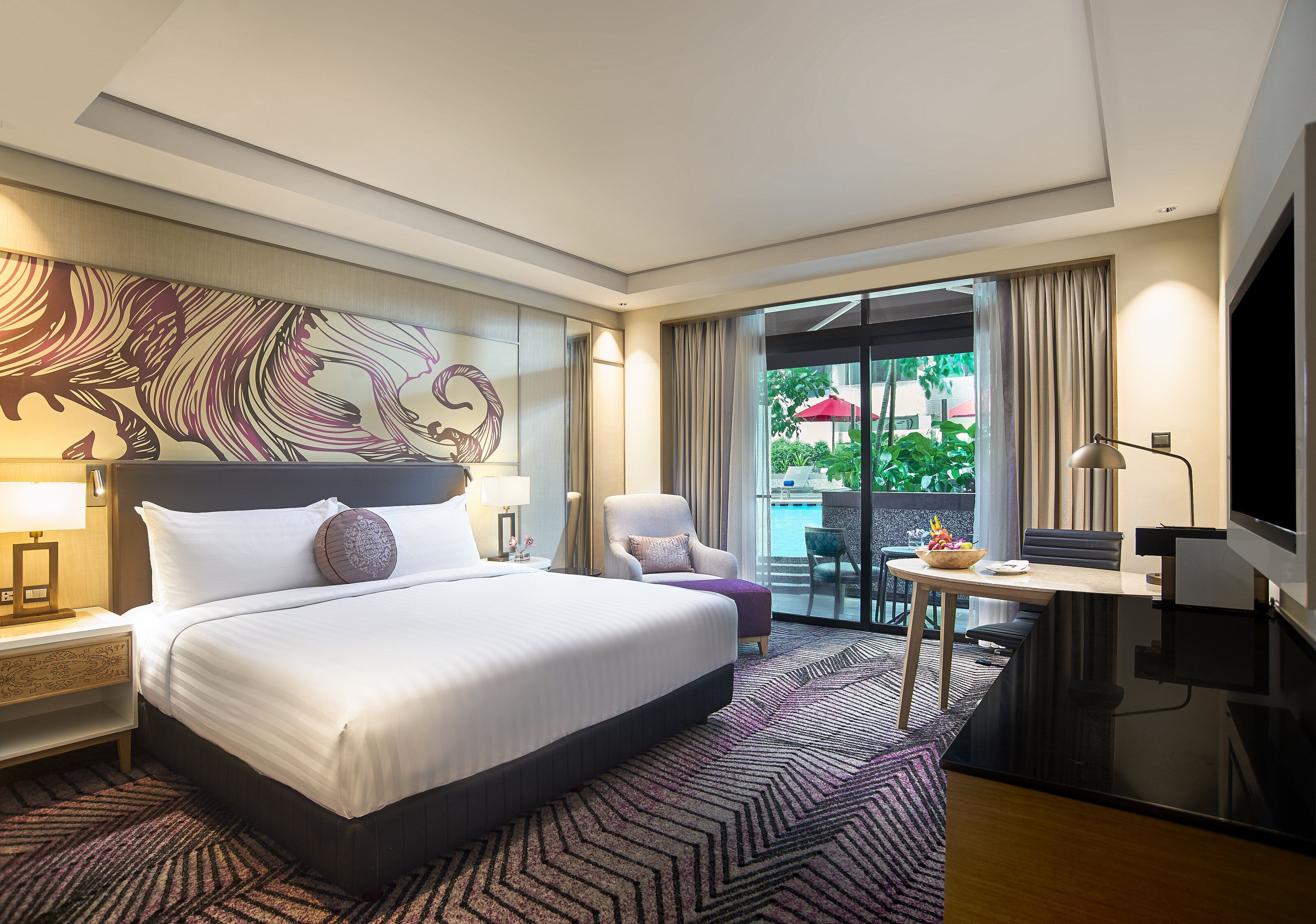 A hotel room with a large bed, a desk, a chair, and a view of the outdoors.