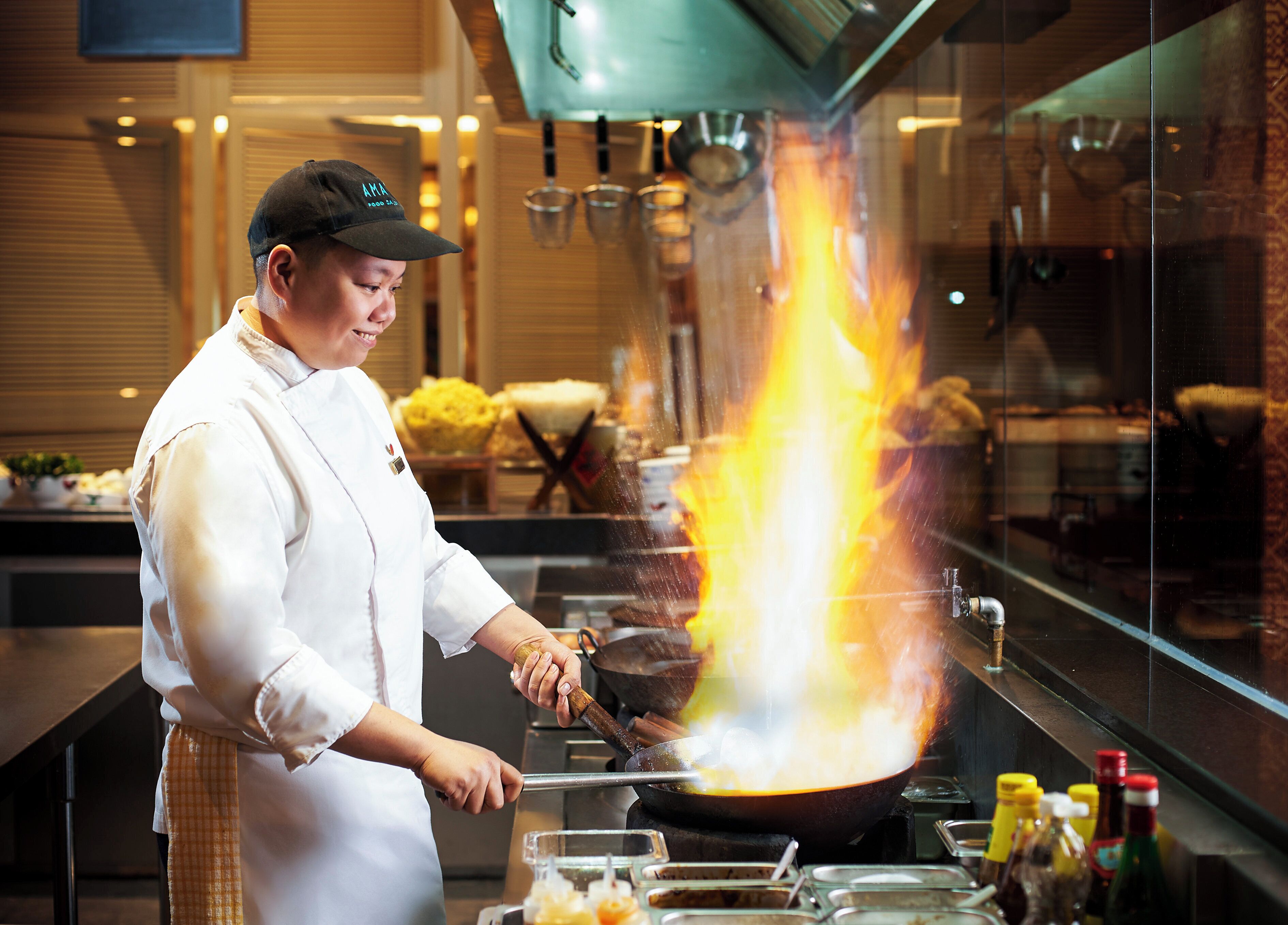 A chef cooking with a large flame in a kitchen.