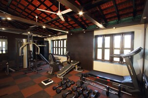 Un gimnasio con cinta de correr, mancuernas y máquinas de pesas.