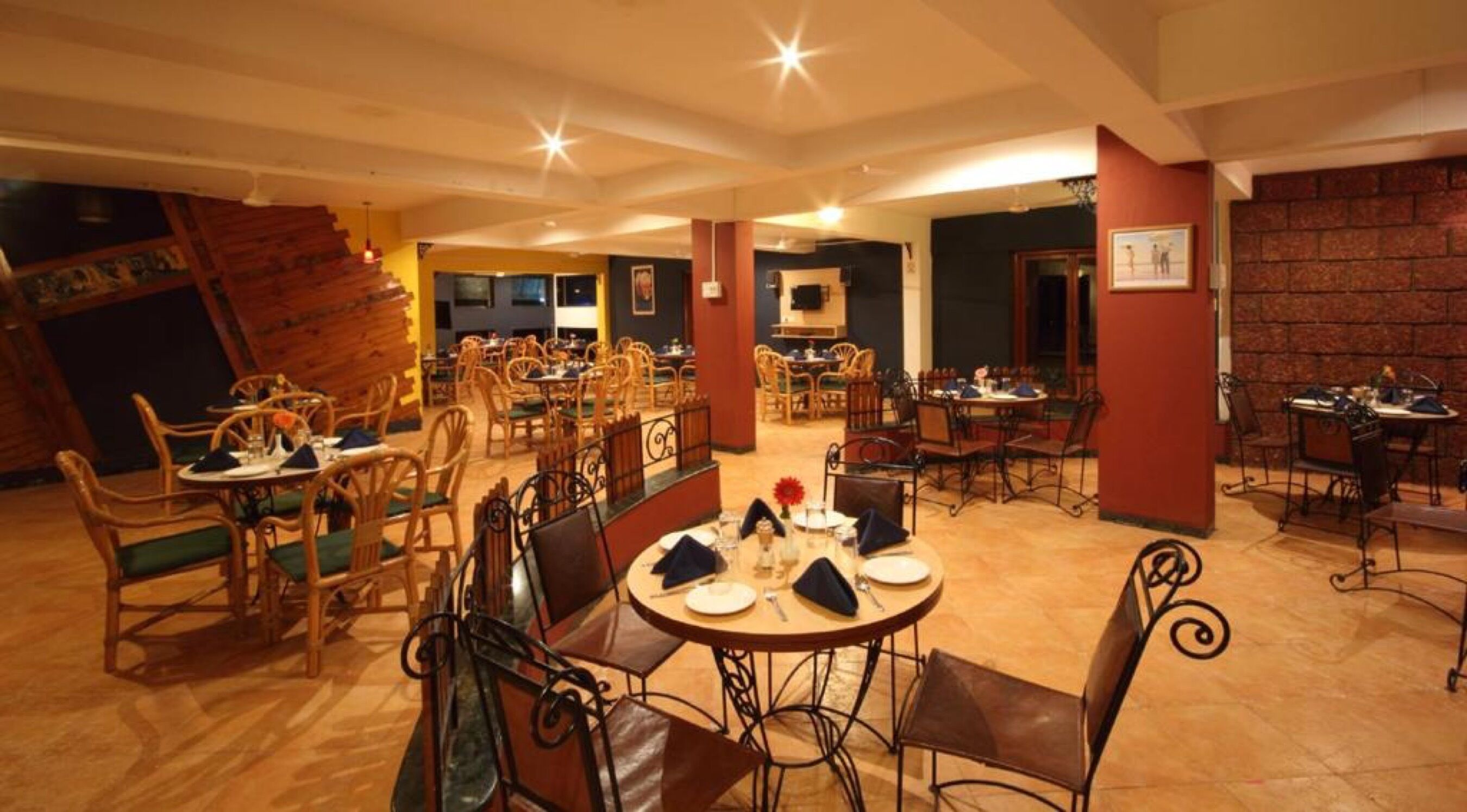 Un restaurante con mesas y sillas de madera, una escalera y una pared de ladrillo.