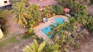 Un quartier résidentiel doté d’une piscine entourée de palmiers et d’une maison avec un toit en tuiles.