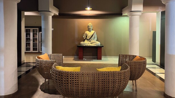 Une statue dans un hall d’entrée, avec des fauteuils en osier et une bibliothèque.