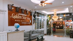 Uma área de recepção de hotel com uma grande placa indicando "Golden Star Hotel Reception", um globo no balcão e um interior moderno com um lustre.