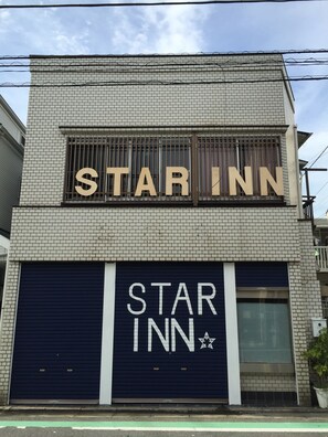 A building with a sign reading "STAR INN" and a closed garage door. - Star Inn Tokyo - Hostel (Tokyo)