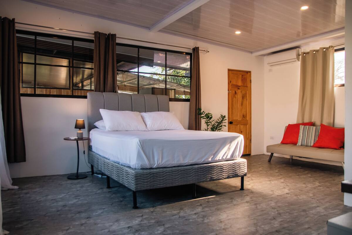 Un dormitorio moderno con cama, mesita de noche y sofá.
